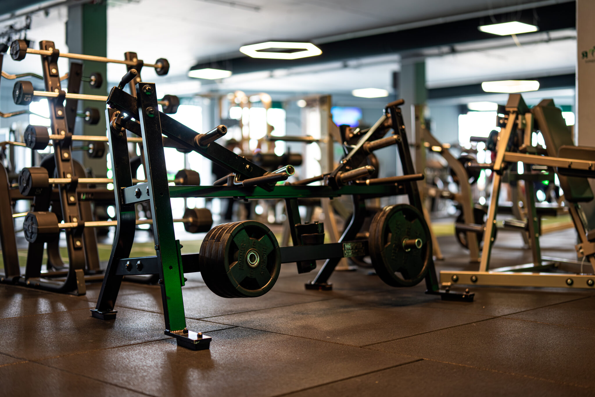 Plate-loaded krachtmachine met trainingsvloer op de achtergrond